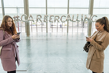 2 young women with phones in front of the lettering #careercalling